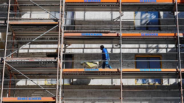Ein Arbeiter geht auf der Baustelle eines Wohnhauses in Berlin mit einer Schubkarre über das Baugerüst. In Deutschland fehlen ...