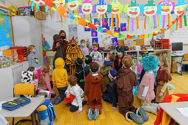 Julia Köb erklärt den Kindern der Klasse 2b an der Fischbacher Grundschule das Häs der Buchhornhexe. Die sind selbst bunt verkleidet.