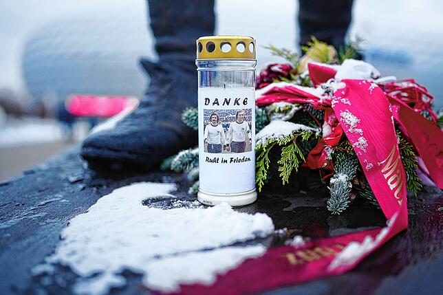 Eine Kerze mit der Aufschrift &bdquo;DANKE Ruht in Frieden&ldquo; steht vor der Gerd-Müller-Statue.