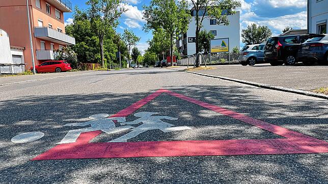 Ein Piktogramm auf dem Asphalt weist darauf hin, dass hier Kinder die Straße queren könnten.