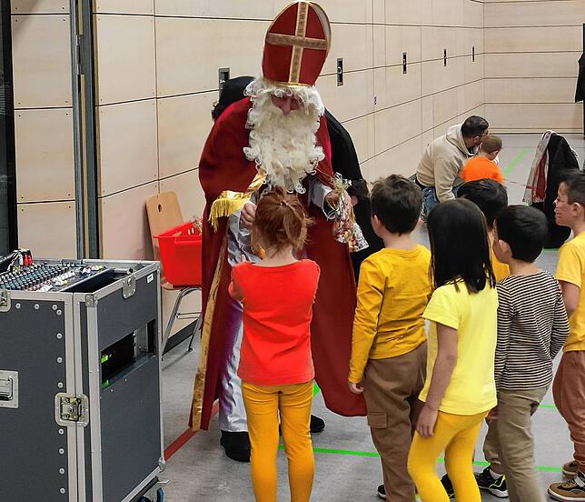 Die Kinder stehen Schlange beim Nikolaus und freuen sich über eine Geschenketüte.
