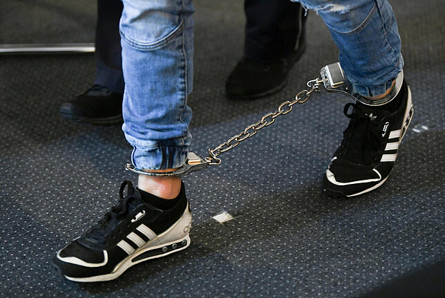 Ein Angeklagter kommt in den Gerichtssaal des Landgerichts mit Fußfesseln. Bild: dpa