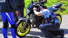 (Symbolbild) Ein Polizist nimmt ein Motorrad ganz genau unter die Lupe.