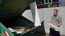 Die meisten Möbel ziehen um, aber diese alten Regale taugen nichts mehr. Manuel Gehner wirft sie in den Müllcontainer.