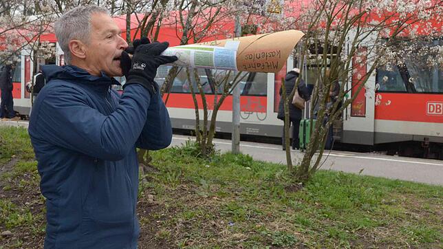 Hier lädt Karl King am Bahnhof mit einer selbst gebastelte Flüstertüte zur Fahrt mit dem Bus ein.