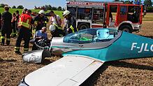 Polizei und Feuerwehr untersuchen den Motor des abgestürzten Kleinflugzeuges.