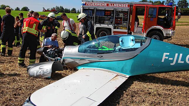 Polizei und Feuerwehr untersuchen den Motor des abgestürzten Kleinflugzeuges.