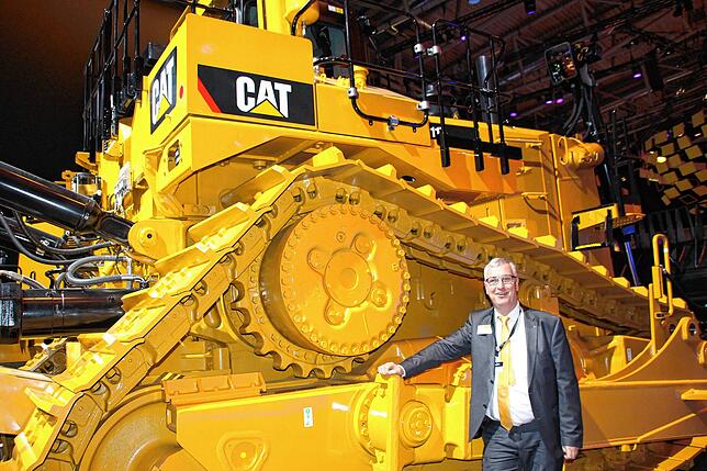 Peter Gerstmann auf der Bauma 2019 in München vor einer Riesen-Raupe.