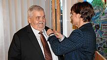 Staatssekretärin Sabine Kurtz heftet Roland Kromer das Verdienstkreuz am Bande an.