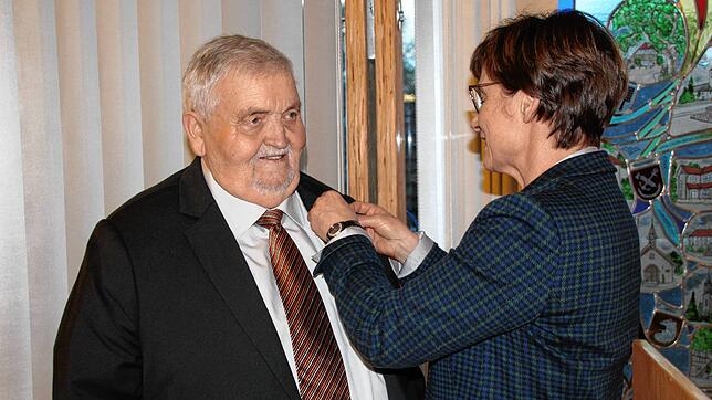 Staatssekretärin Sabine Kurtz heftet Roland Kromer das Verdienstkreuz am Bande an.