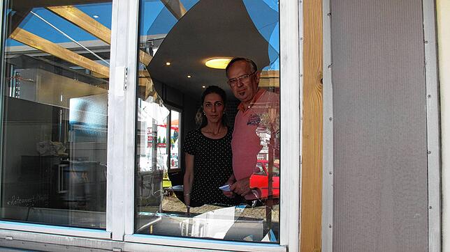 Jelena und Damir Dokic schauen durch die zerstörte Fensterscheibe ihres Imbiss, in den sie viel Geld und Arbeit investiert haben.