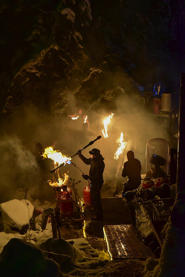 Von der Seite aus kann man sehen, dass der Feuerkünstler nicht alleine am Werk ist. Im Dunkeln arbeiten die Helfer, zudem sind die ...