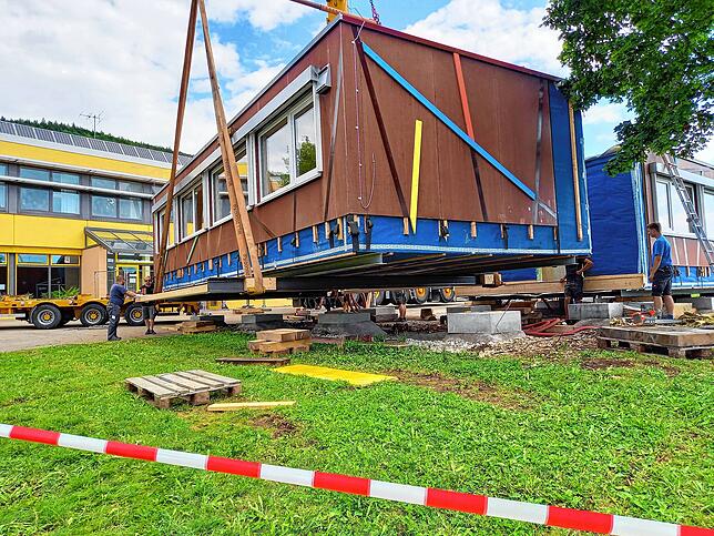Es hat geklappt: Vor der Eichbergschule in Blumberg hängt das erste mobile Klassenzimmer am Kranhaken und wird auf den Tieflader ...