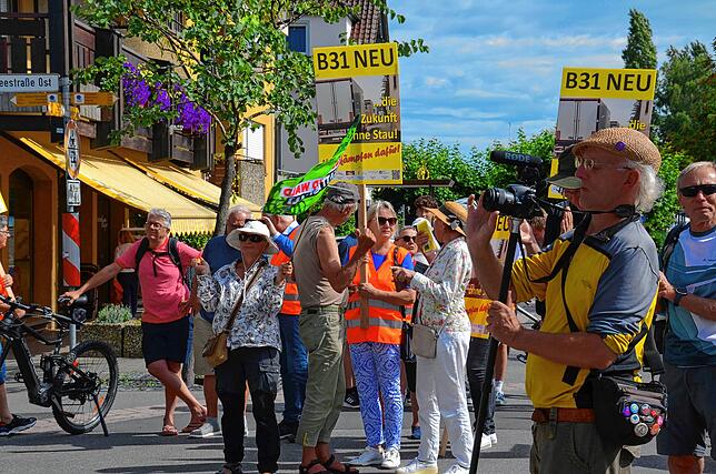 Eine Vertreterin der Tour de Natur hat sich mit ihrer Flagge vor die Schilder des Bündnisses Pro B31-neu platziert.