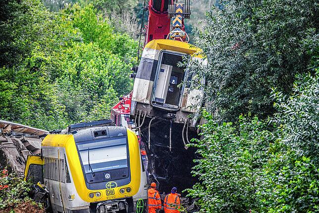 Mit einem Kran wird an der Unfallstelle, an der ein Regionalzug entgleist ist, ein Waggon angehoben. Ein Regionalexpress war am ...