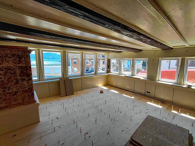 Blick von innen in die große Stube mit dem Widerhergestellten Fensterband. Im frisch verlegten Holzdielenboden stecken noch die ...