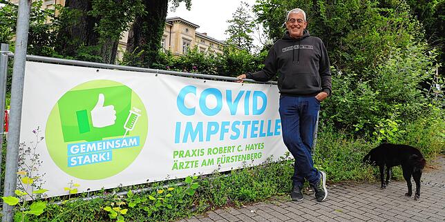 Hausarzt Robert Hayes vor dem Banner, das auf seine Impfstelle im Vereinsheim des Musikvereins Eintracht Petershausen hinweist.
