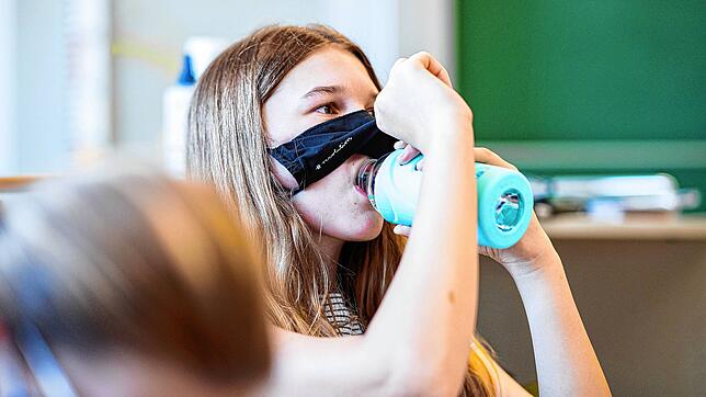 Eine Schülerin hebt ihre Mund- und Nasenmaske an um etwas zu trinken. In Baden-Württemberg ist das Maskentragen für Schüler ab Klasse 5 ...