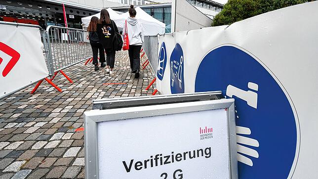 Studenten laufen am Eingang der Hochschule der Medien an eine Kontrollstelle für einen Nachweis über eine Corona-Impfung oder -Genesung. ...