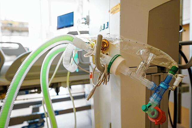 Ein Beatmungsgerät steht vor einem Bett in einem Patientenzimmer auf der Intensivstation einer Klinik.
