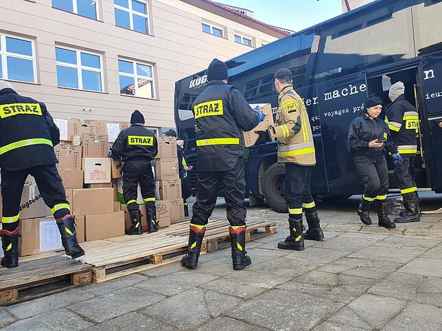 Polnische Feuerwehrleute helfen beim Entladen des Busses.