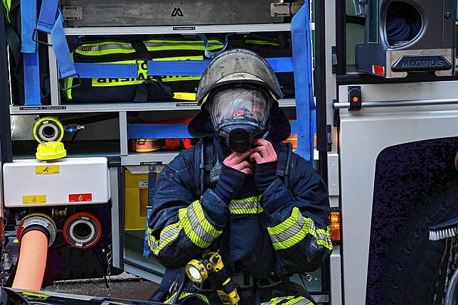 Ein Feuerwehrmann mit rußgeschwärztem Helm und Atemschutzmaske nach seinem Einsatz in der brennenden Wohnung.