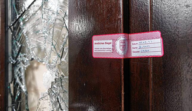 Ein Siegel der Polizei klebt im Stadtteil Alsterdorf am Eingang zu dem Gebäude der Zeugen Jehovas neben einer beschädigten Glasscheibe.