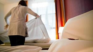 Eine Servicekraft macht Betten in einem Hotel. (Symbolbild)