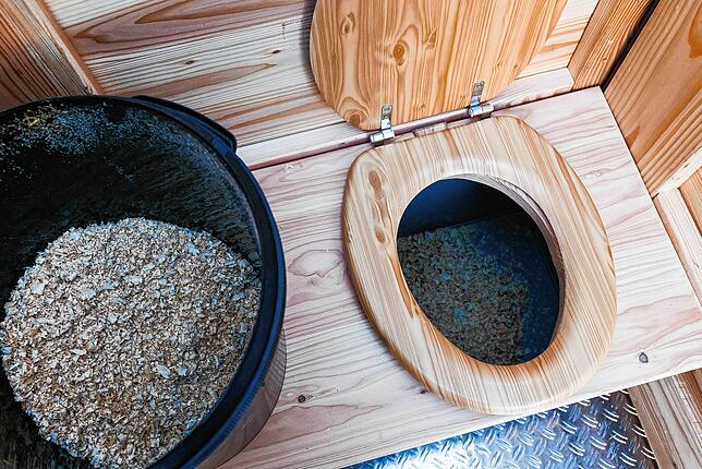 Bei einer Komposttoilette werden Holzspäne nach dem „Geschäft“ ins WC geschaufelt.