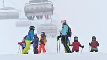 Archiv: Eine Skilehrerin steht am 09.01.2016 auf dem Feldberg mit ihrer Kindergruppe zusammen, während im Hintergrund eine Sesselbahn zu ...