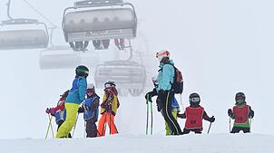 Archiv: Eine Skilehrerin steht am 09.01.2016 auf dem Feldberg mit ihrer Kindergruppe zusammen, während im Hintergrund eine Sesselbahn zu ...