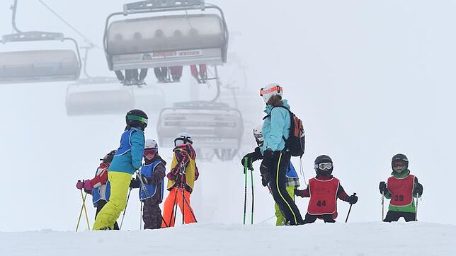 Archiv: Eine Skilehrerin steht am 09.01.2016 auf dem Feldberg mit ihrer Kindergruppe zusammen, während im Hintergrund eine Sesselbahn zu ...