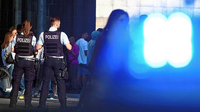 Einsatzwagen der Polizei mit Blaulicht und Polizeibeamte bei einem Einsatz.