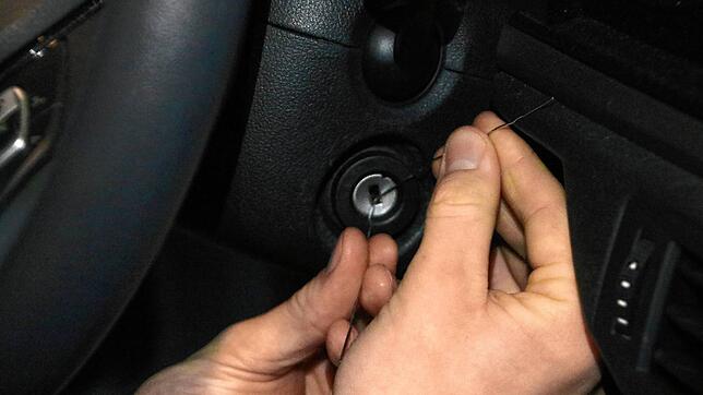 Ein Autodieb versucht die Zündung mit zwei Drähten zu starten (nachgestellte Szene). Die Polizei hat nach mehreren Autodiebstählen in ...