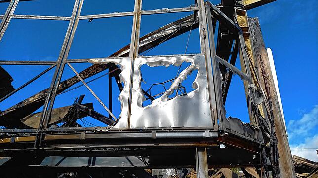 Von der Brandhitze an der Fassade eines Lagergebäudes zerschmolzenes Metall.
