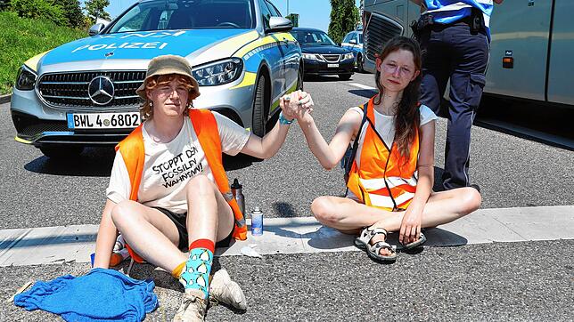 Eileen Blum aus Allensbach (rechts) sitzt am 11. Juli auf der Europastraße (B33) in Konstanz. Sie ist angeklebt an Regina Stephan, deren ...