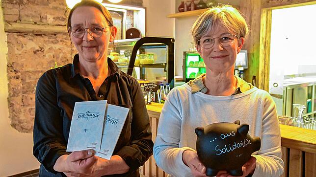Kirsten Heinzmann (links) und Karin Ettwein zeigen die Gutscheine und das Spendenschwein für Gäste mit kleinem Budget im Café Vielfalt. ...