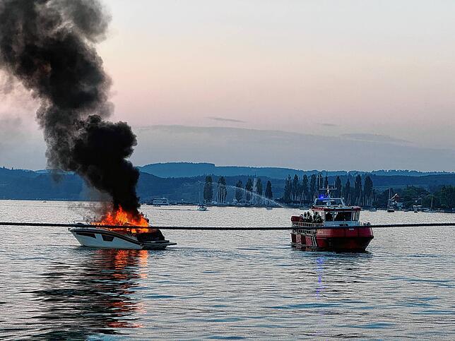 Von einem Feuerlöschboot aus wird der Brand, der hohe Flammen schlägt, von den Einsatzkräften der Feuerwehr angegangen.