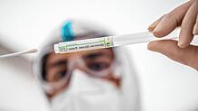 In einem Corona-Testzentrum steckt ein Mitarbeiter ein Wattestäbchen nach einem PCR-Abstrich zum Test auf Covid-19 in ein Röhrchen. Für ...