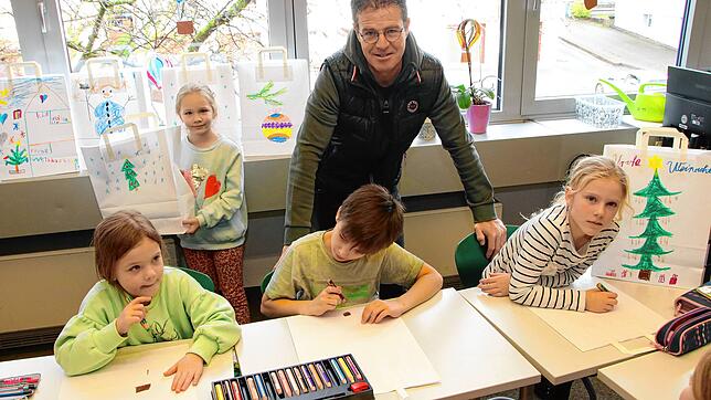 Holger Ahlers mit Kindern der Klasse 2c der Weihermattenschule. Sie sind dabei, Papiertüten zu bemalen, in denen Ahlers zu Weihnachten ...