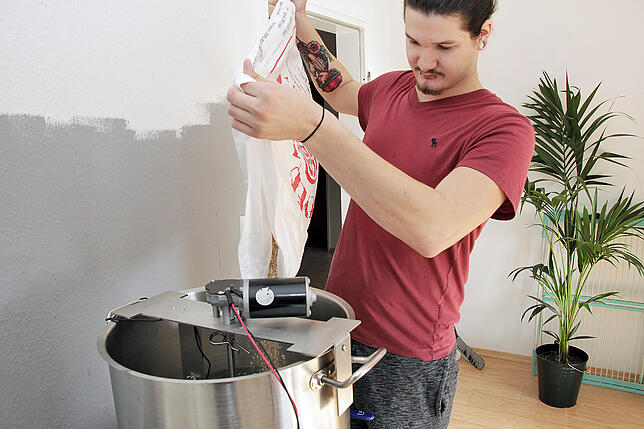 Lukas Kromer schüttet das Malz in den vorgeheizten Braukessel.