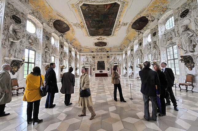 Eine Besuchergruppe steht im Kaisersaal im Schloss in Salem.