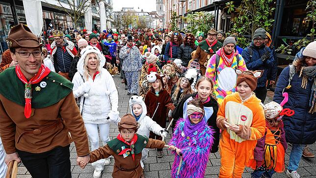 Mit vereinten Kräften wird der Baum zu seinem Bestimmungsort gebracht. Zahlreiche bunt verkleidete Kinder packen kräftig mit an und ...