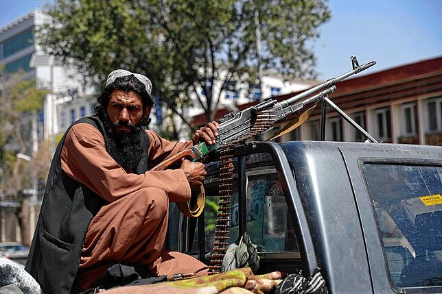 Ein Taliban-Kämpfer mit einem Maschinengewehr vor dem Haupttor zum Präsidentenpalast in Kabul.