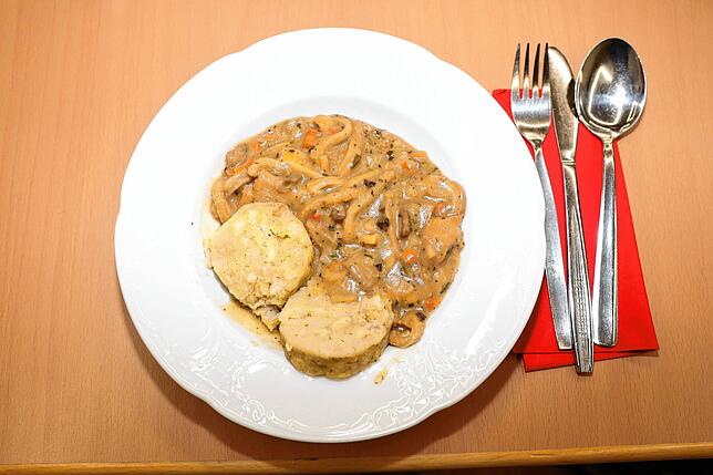 Besteck liegt neben einem Teller Kutteln mit Champignonrahmsoße und Serviettenknödeln. (Archivbild)