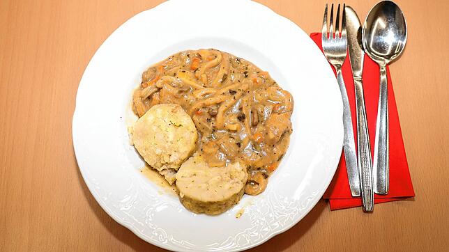 Besteck liegt neben einem Teller Kutteln mit Champignonrahmsoße und Serviettenknödeln. (Archivbild)