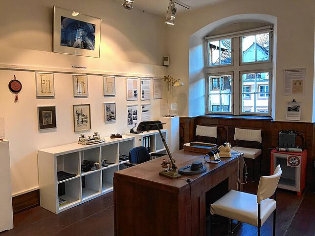 Ein Blick in die Ausstellung in der Alten Metzig mit historischem Schreibtisch und Informationen über das Rathaus.