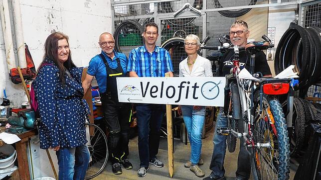 Karin B. (links) lässt den Reifenschaden an ihrem Fahrrad bei Velofit reparieren. Teil der Sozialen Fahrradwerkstatt sind (von links): ...