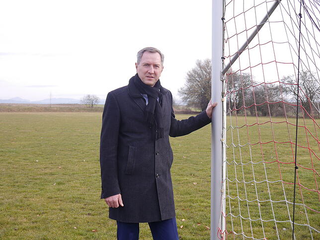 Bürgermeister Michael Schmitt auf dem Kirchdorfer Sportplatz. Hier soll das Gewerbegebiet Kreuzäcker entstehen.