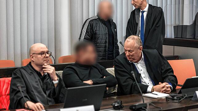Der Hauptangeklagte (hinten, links) spricht im Gerichtssaal mit seinem Verteidiger Oliver Doelfs (hinten, rechts), während vorne ein ...